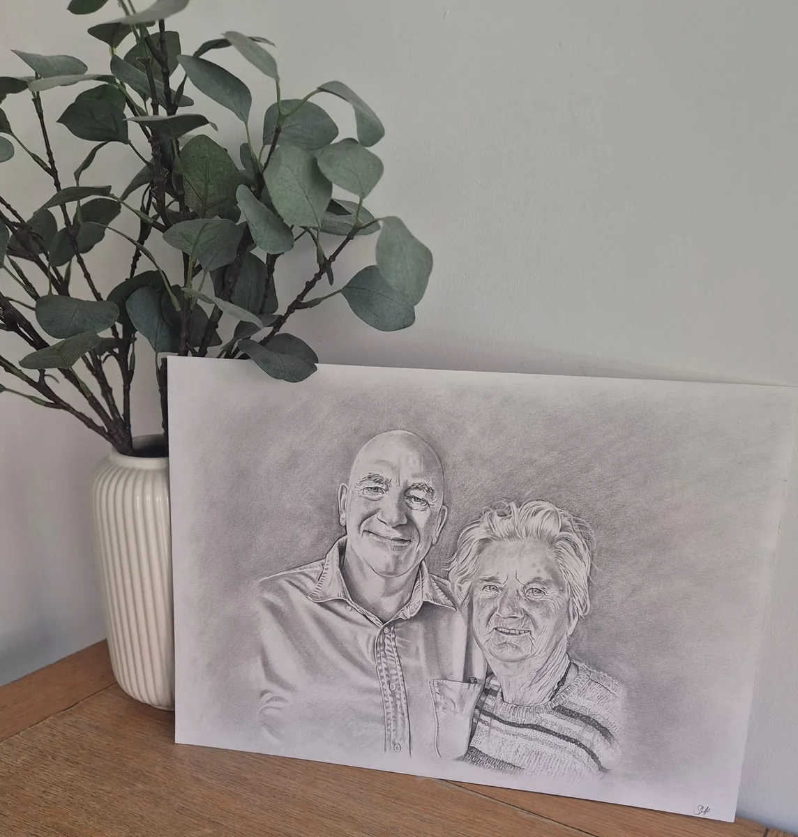 Pencil portrait commission of a man and an elderly woman, drawn from a family photo