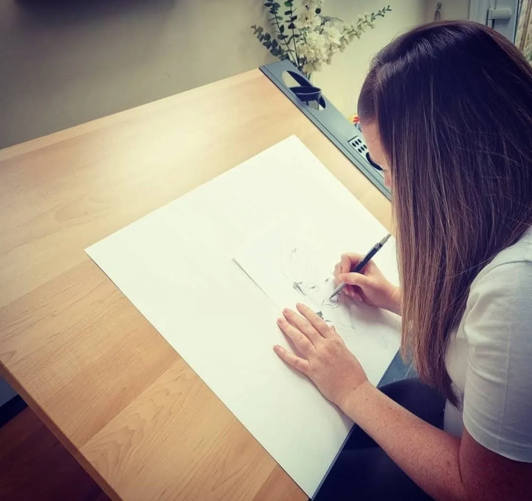 Sarah Mallett drawing a pencil portrait commission at her desk in Devon
